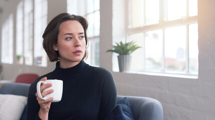 Beautiful woman looking out window holding cup of coffee