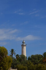 Fototapeta na wymiar Faro de la playa de Vilanova entre árboles y palmeras