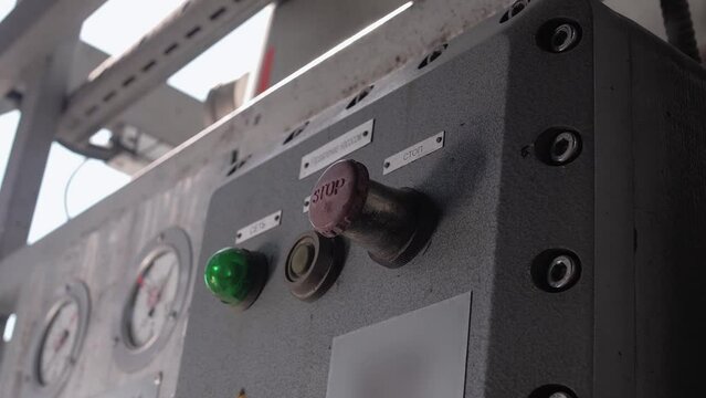 Employee hits the big red button on the electrical control panel at the factory. Close-up 