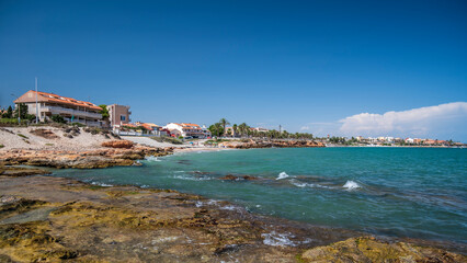 Rocky shore along a Spanish beach.  The clear sea is lapping at the shore