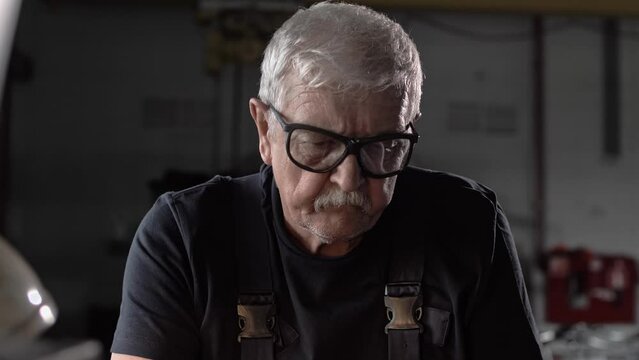 Cinematic portrait of an elderly locksmith working at a lathe in a factory 