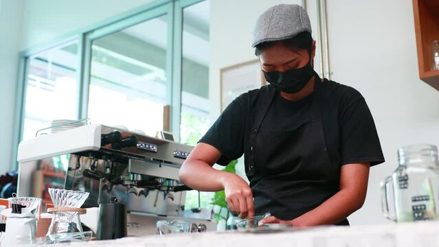 Portrait Asian female owner small business wearing protective face mask making coffee or green tea at coffee café.