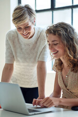 two business women using laptop computer working in office team leader sharing ideas with colleague...