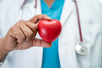 Doctor holding a red heart in hospital ward, healthy strong medical concept.