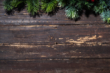 Christmas and New Year greeting card simple background. Spruce branches on dark old rustic wooden table top view copy space