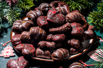 Christmas lebkuchen mix cookies, traditional Xmas chocolate Gingerbreads with holiday decoration, gifts, Christmas tree branch on dark green table top view copy space
