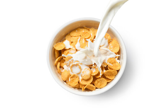 Top view of Pouring milk into the bowl of corn flakes isolated on white background.