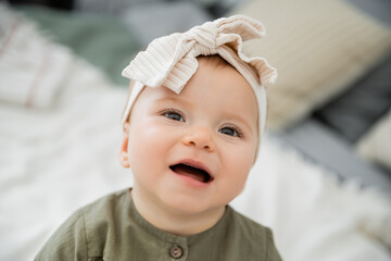 portrait of happy baby girl in pastel pink headband with bow.