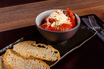 Polpette tradizionali napoletane servite in una ciotola con ragù di pomodoro e formaggio grattugiato con contorno di pane in una braceria napoletana