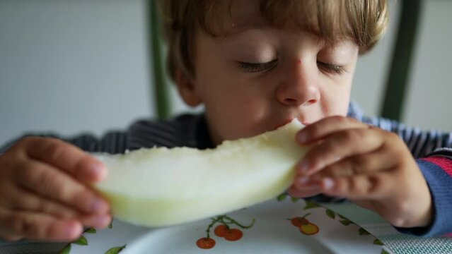 Child eating melon fruit hungry little boy eats healthy snack