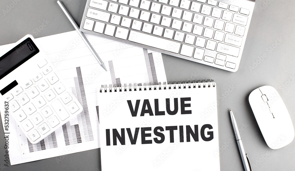 Poster value investing text written on notebook on grey background with chart and keyboard, business concep