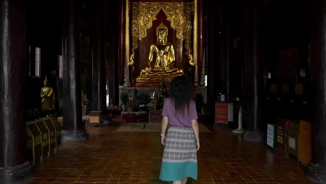 Camera follows the woman walks in the Thai temple 