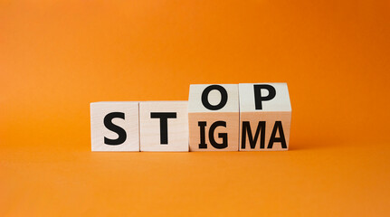 Stop and Stigma symbol. Businessman hand points at wooden cubes with words Stop and Stigma....