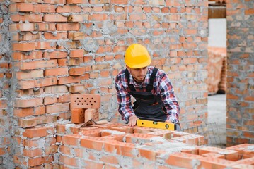 Yellow colored hard hat. Young man working in uniform at construction at daytime.