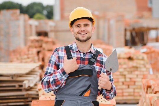 construction mason worker bricklayer installing red brick with trowel putty knife outdoors.