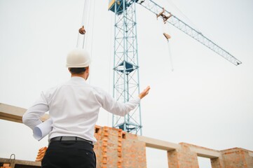 Architect at a construction site with blueprints