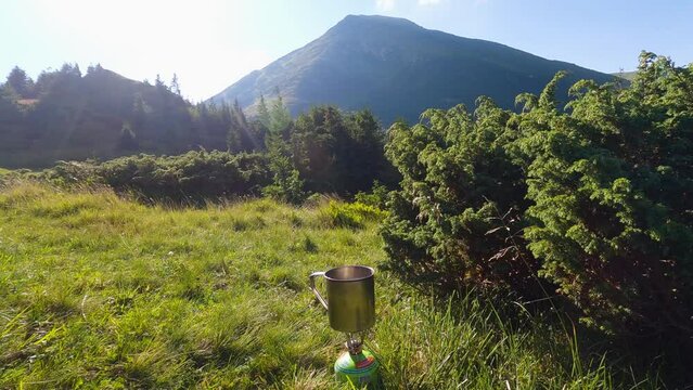 Cooking soup on tourist gas burner with mountain view