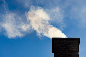 Woodsmoke coming out of the chimney of an old farmhouse climbs into a clear, cold morning sky