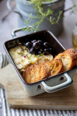 Baked camembert cheese with thyme, baguette , grapes and olive oil.