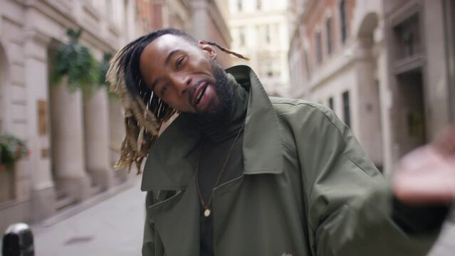 Camera follows a happy and confident young man as he turns to camera to beckon us to follow him, in slow motion