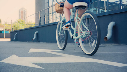 Cropped view of woman riding bicycle on urban street.