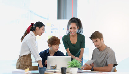 Group of young asian business people in smart casual wear working together in creative office using laptop.