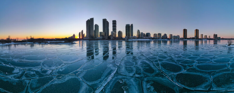 defaultHorizontal wide angle aerial large panorama of frozen lake with Toronto Etobicoke neighborhood city skyline with highrise condo buildings in the background shot at sunset hour.