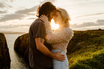 Couple hugging against sundown sky