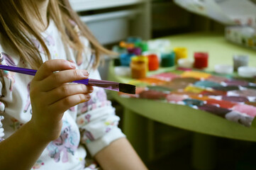 a child draws with paints multi-colored tones gouache brush