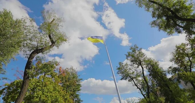 The Ukrainian flag flutters in the wind in slow motion general plan. Ukrainian flag on a flagpole against the sky