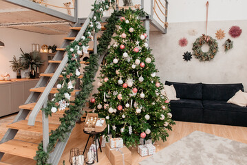 Fototapeta premium Christmas room in the house with a staircase and a large Christmas tree decorated with New Year's toys