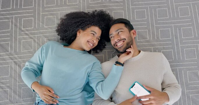Phone, music earphones and couple on bonding on floor in house or home and listening to relax podcast. Top view, happy smile and interracial black woman and asian man love on radio mobile technology