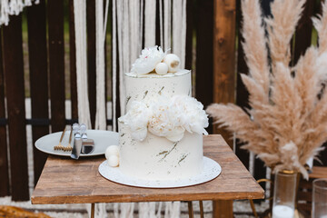Large luxury wedding cake on a background of a beautiful arch in the style of boho. Wedding dessert...