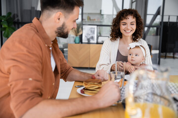 bearded man having breakfast with happy wife and baby daughter.