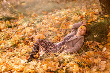 Stylish young woman lies in autumn leaves