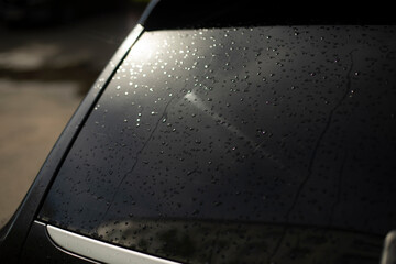 Black car rear window. Drops on rear window of transport. Light on car window.