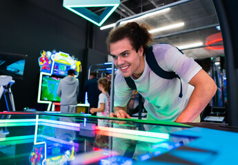 A smiling young man playing games at arcade entertainment center.