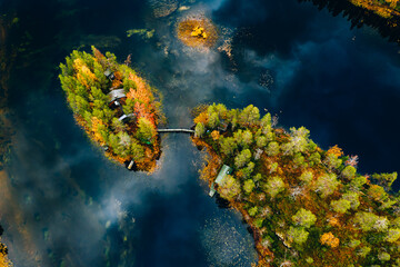 Aerial view of fall autumn colors forest and blue lake with island in rural Finland