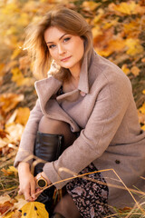 Fototapeta na wymiar Portrait of a young woman in a coat on a background of yellow leaves in an autumn park