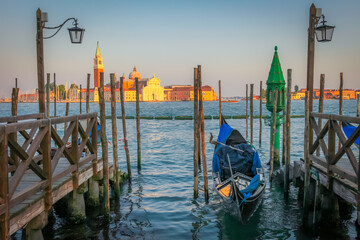 Fototapeta na wymiar Gondole docked by wooden mooring poles in grand canal, Ethereal Venice, Italy