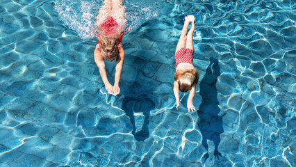 Happy family in swimming pool. Child with young woman swim, dive in pool with fun - jump deep down...