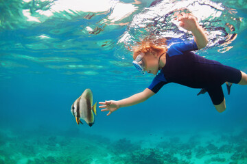 Happy family - active kid in snorkeling mask dive underwater, see tropical fishes in coral reef sea...