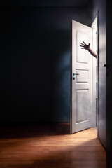 Scary horror door with hand of ghost, zombie or evil creepy man. Spooky monster from hell. Halloween or nightmare. Dark room in haunted house. Light and smoke from open closet. Fantasy, thriller movie