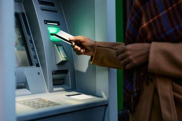 Close up of black woman using credit card while withdrawing cash at ATM. - obrazy, fototapety, plakaty