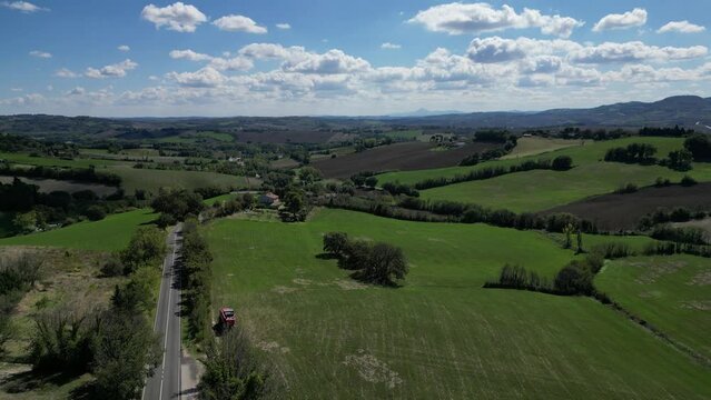 Verdi colline con cielo nuvoloso, con una piccola strada che li costeggia