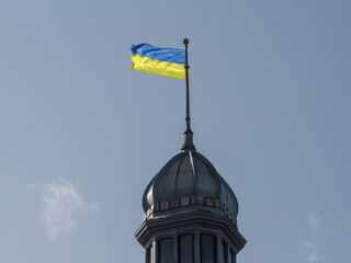 The flag of Ukraine develops on a flagpole against a background of clear sky