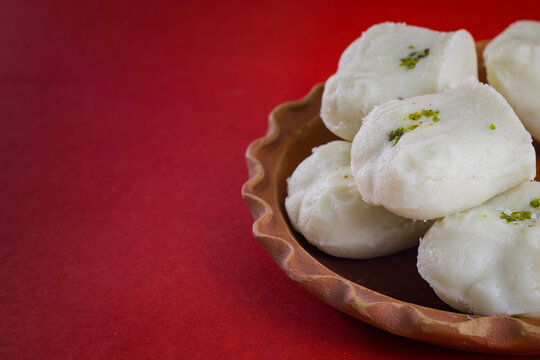 Bengali sweet sandesh served on a clay plate for celebration of indian festivals. white jolbhora or talsaash sandesh, made of cottege cheese.close-up shot in red background.