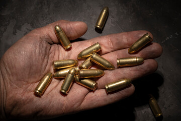 9mm pistol cartridges in the palm of a man. - obrazy, fototapety, plakaty