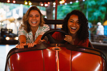 Fototapeta na wymiar Multiracial women laughing while spending time in attraction park