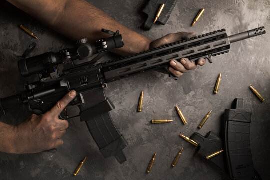 Rifle Ar 15 in the hands of a soldier, magazines and cartridges nearby.